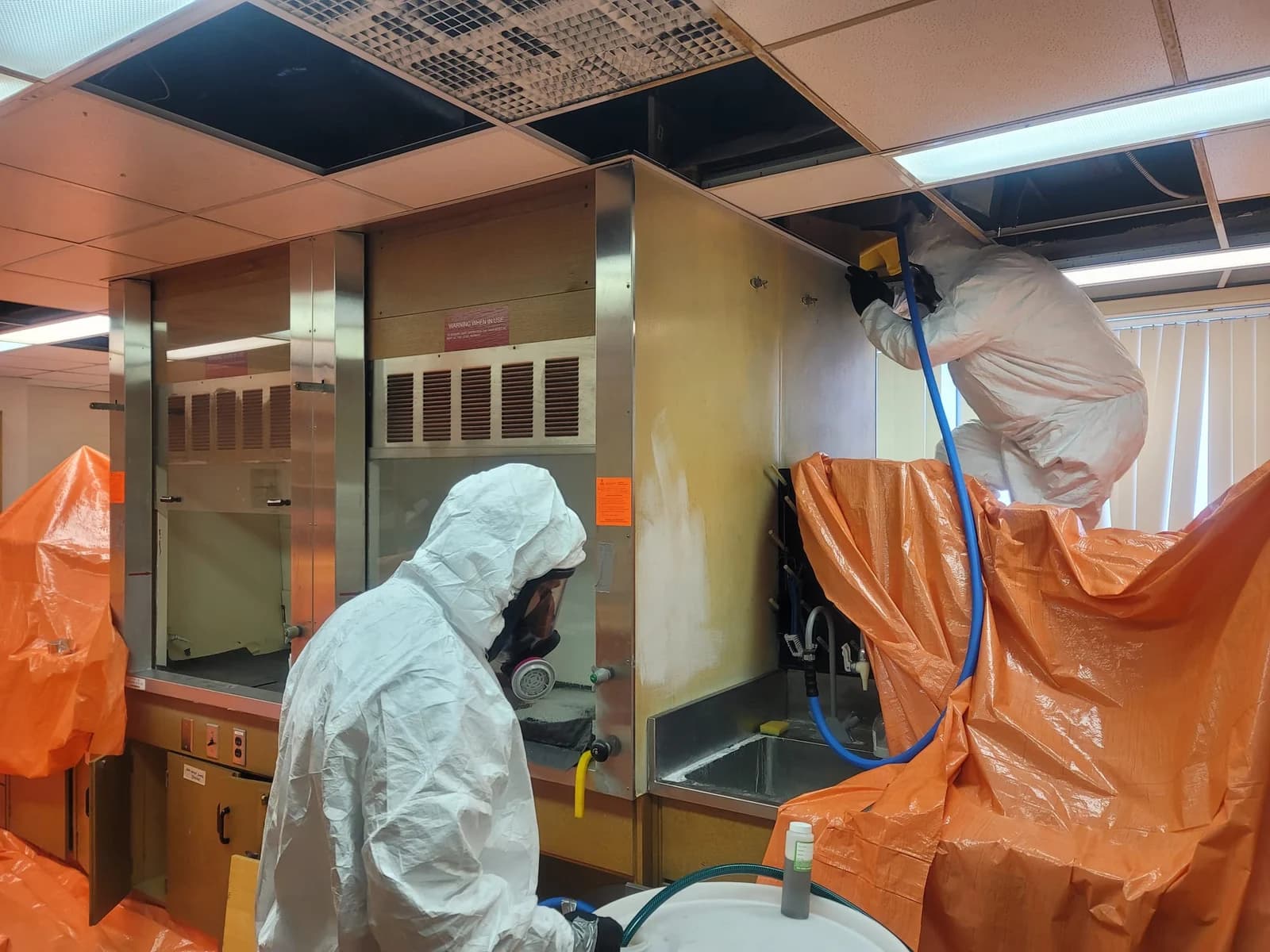 Technicians working under containment during laboratory decontamination